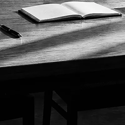 Team an einem Tisch mit Notizbüchern vor einer hellen Projektionsfläche