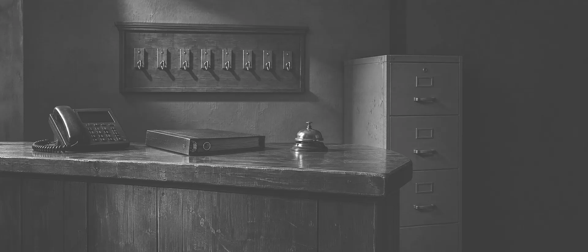 Empfangstheke am Abend mit Schlüsselbrett, Telefon, Klingel und Aktenschrank, hartes Streiflicht