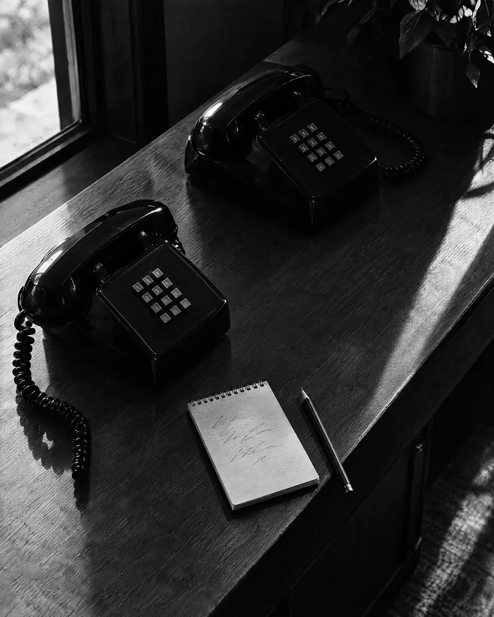 Zwei Telefone und ein Notizblock mit kurzen Strichen auf einer Theke