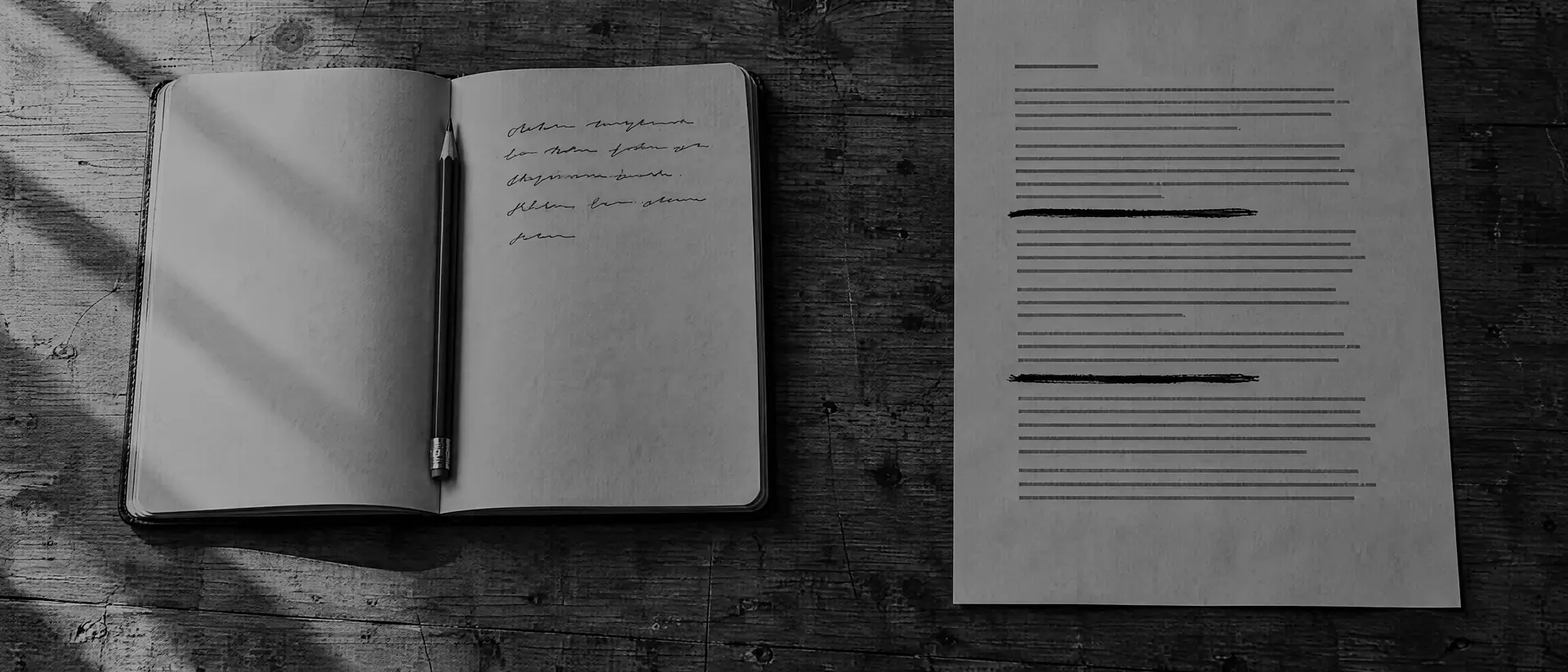 Aufgeschlagenes Notizbuch mit Bleistift und ein bedrucktes Blatt mit durchgestrichenen Zeilen auf einem Holztisch