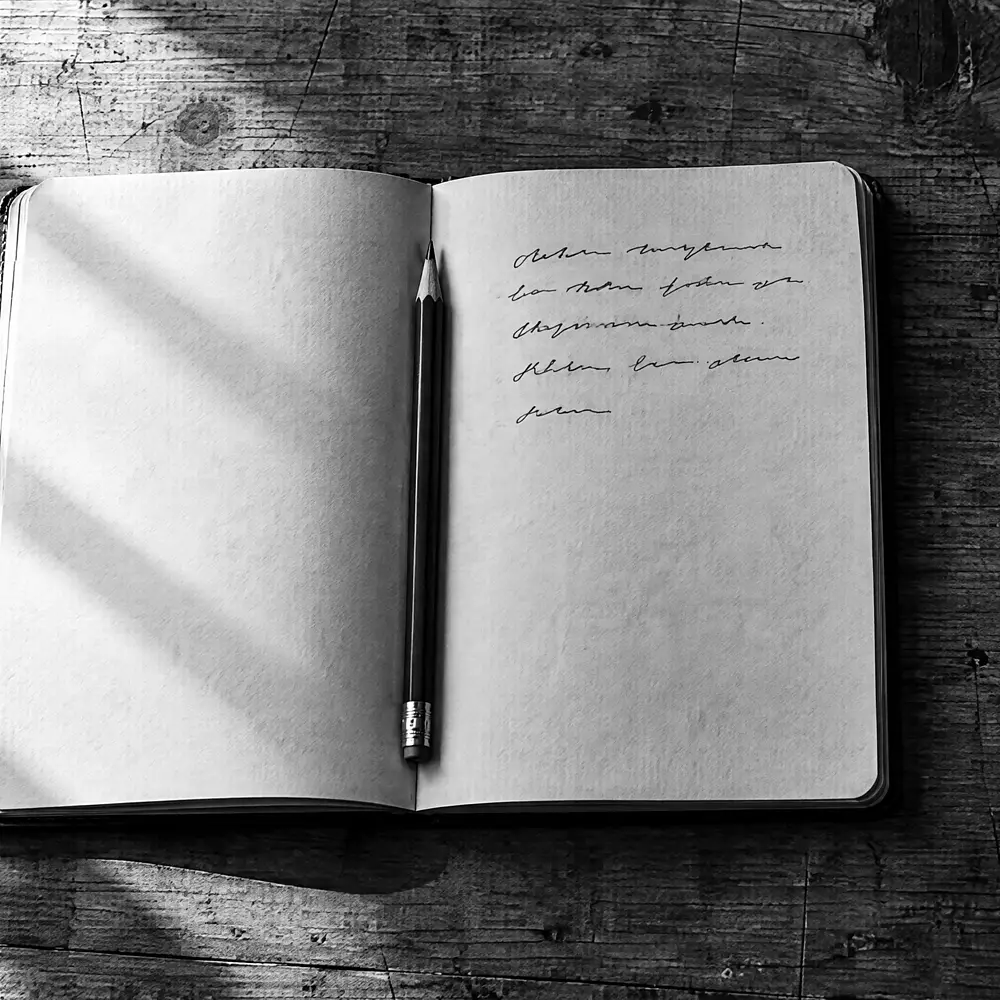 Aufgeschlagenes Notizbuch mit handschriftlichen Notizen auf einem Werktisch, der Bleistift liegt in der Falz